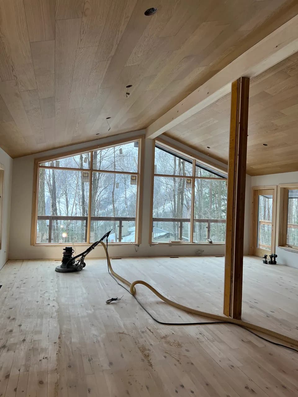 Vaulted wood-ceiling interior with lakeview windows and hardwood floor